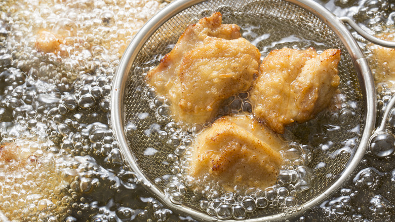 Deep frying chicken in bubbling oil