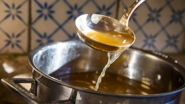 Thin broth pouring out of a ladle