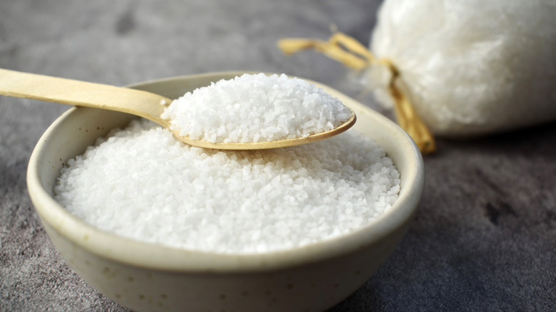 Large salt crystals in a spoon resting on a bowl