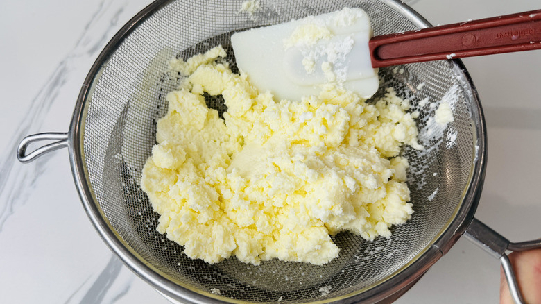 Straining homemade butter in sieve