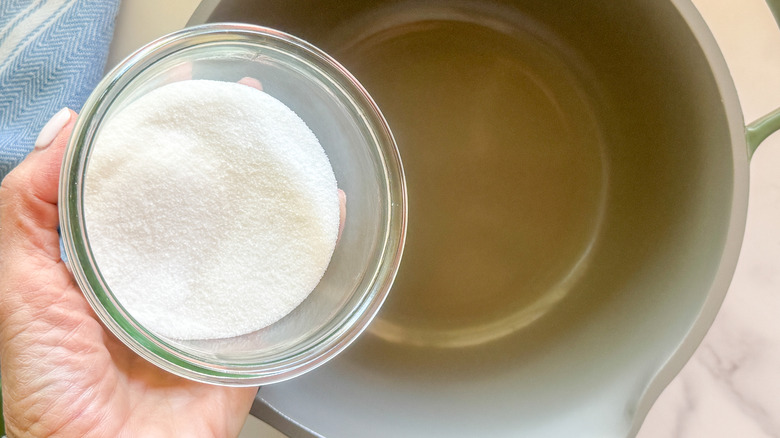 hand adding sugar to pot