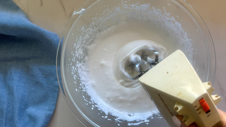 hand using beater in bowl