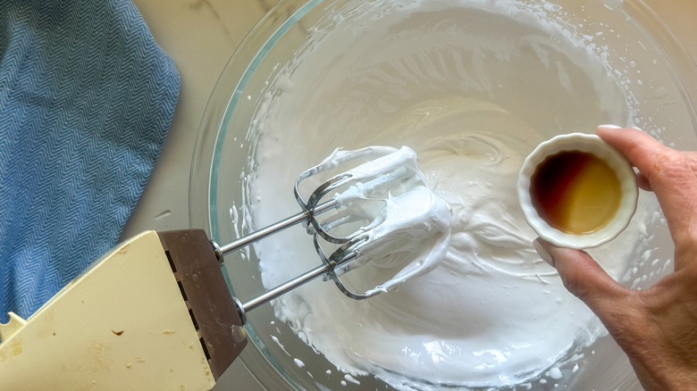 hand adding vanilla to bowl