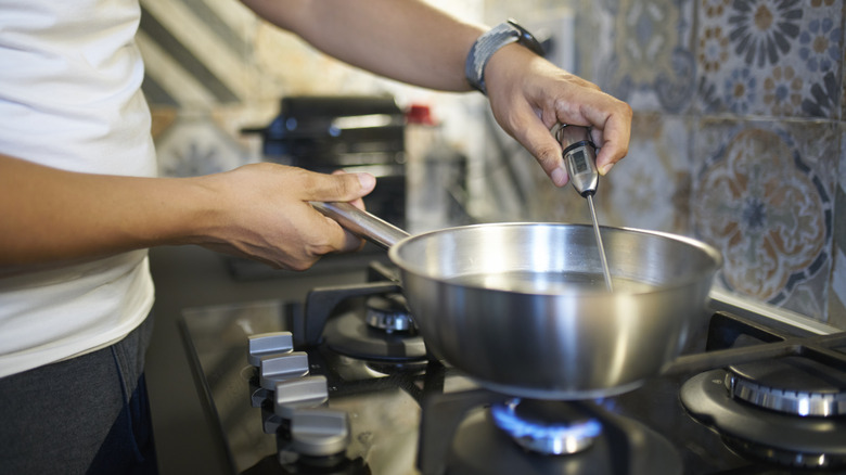person holding thermometer inside cooking pot
