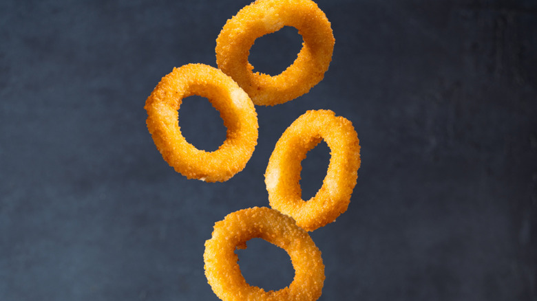 onion rings falling against dark background