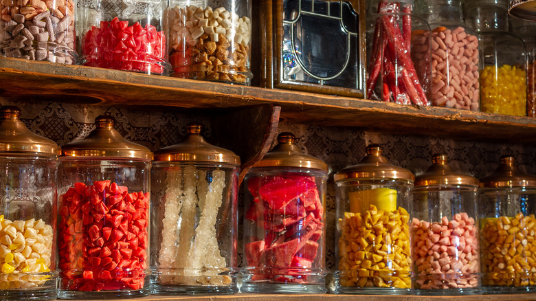 Jars of candy in glass jars with copper lids on shelves in a candy shop