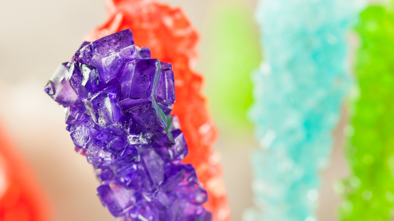 Close-up photo of purple rock candy with other colors of rock candy in the background