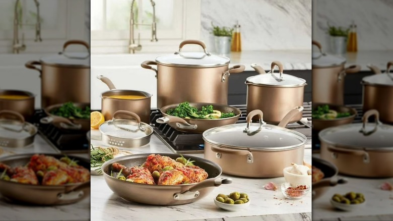 Five Circulon pots and pans on a stovetop with sauteed broccoli in the middle pan