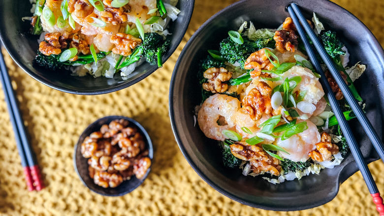 Honey walnut shrimp bowls with chopsticks and walnuts on table
