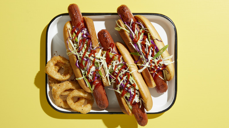 three hot dogs with onion rings on tray