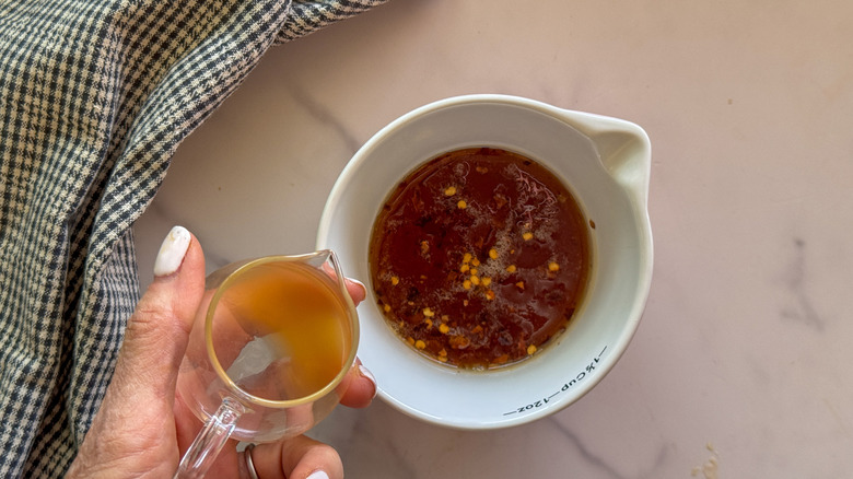 hand adding vinegar to bowl