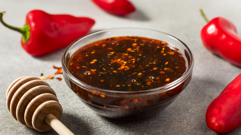 a closeup of hot honey in a small glass ramekin with chilli peppers in the background
