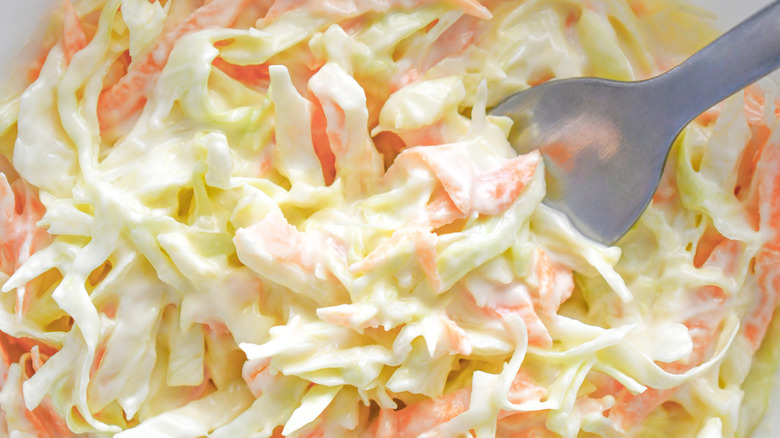 a close-up photo of coleslaw with carrot and cabbage on fork