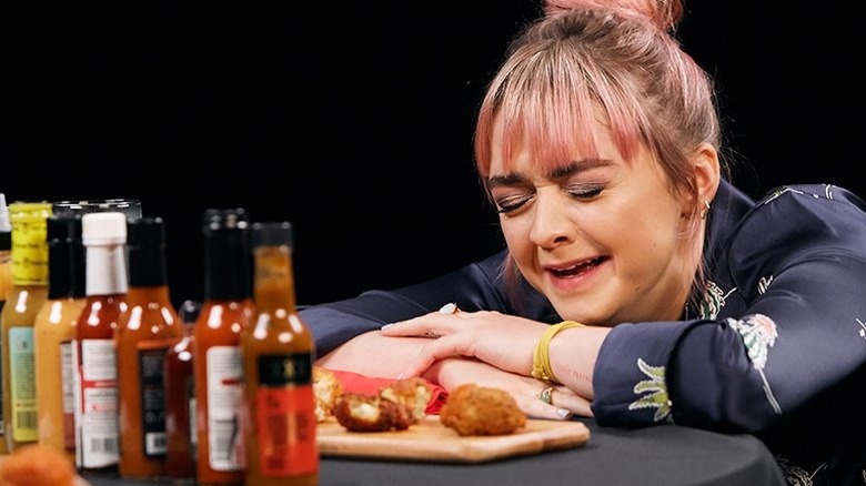Maisie Williams lays on table during Hot Ones