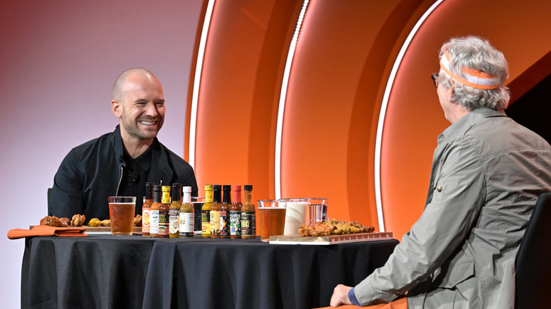 Hot Ones host Sean Evans across the table from his guest