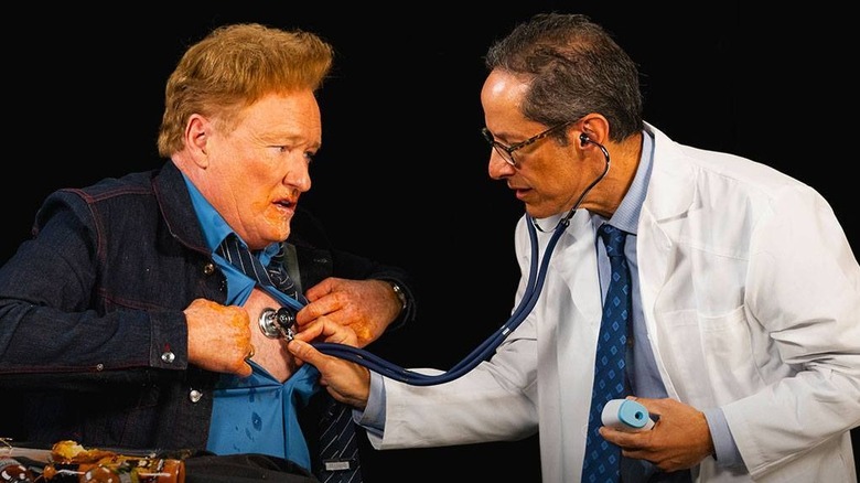 doctor puts stethoscope on Conan's chest during Hot Ones