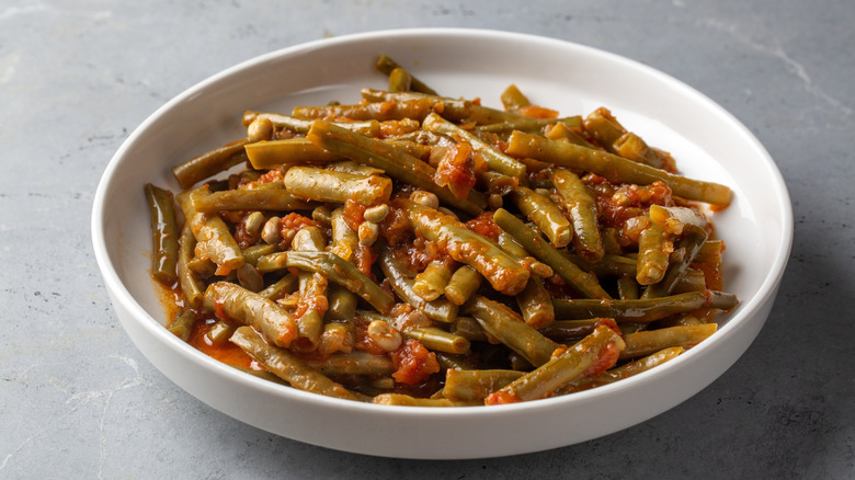 A bowl of green beans stewed with tomatoes.