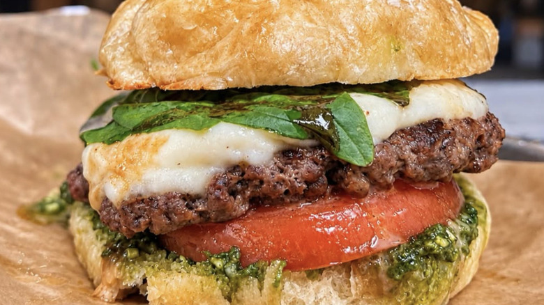 burger with fresh basil, beef and cheese, tomato and pesto