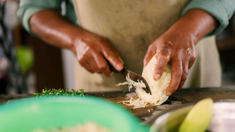 Person cutting cabbage on a cutting board.