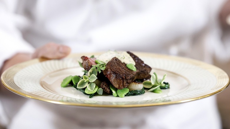 steak and other foods on gold white house china plate