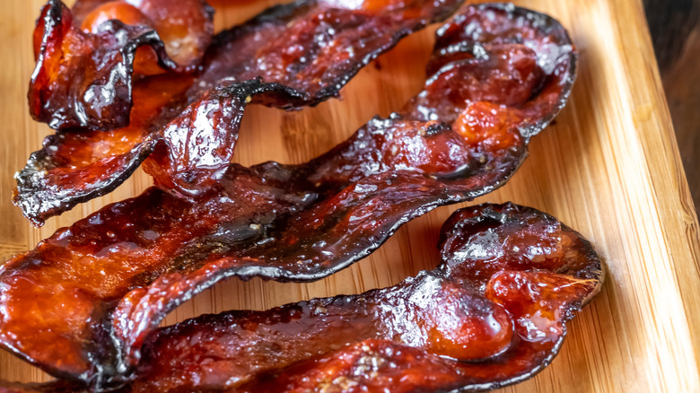 Glazed bacon on a wooden cutting board.