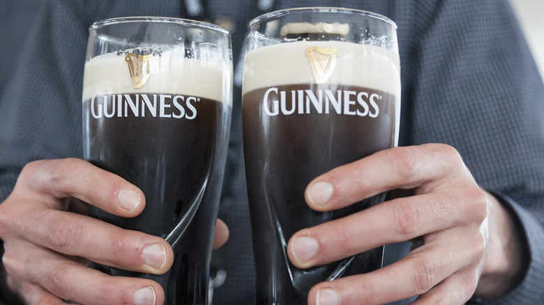 Man holding two Guinness beers.