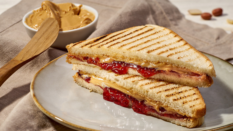 Grilled PB&J served on a plate next to a bowl of peanut butter