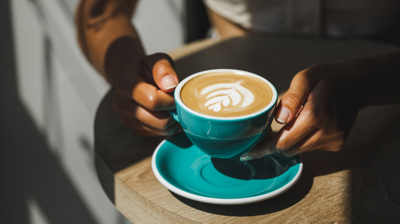 Person holding cup of coffee with latte art