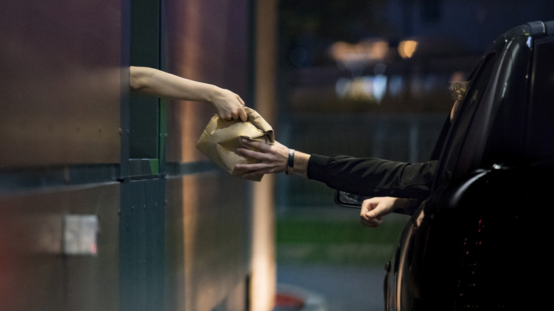 Customer receiving food at a drive-thru window at night