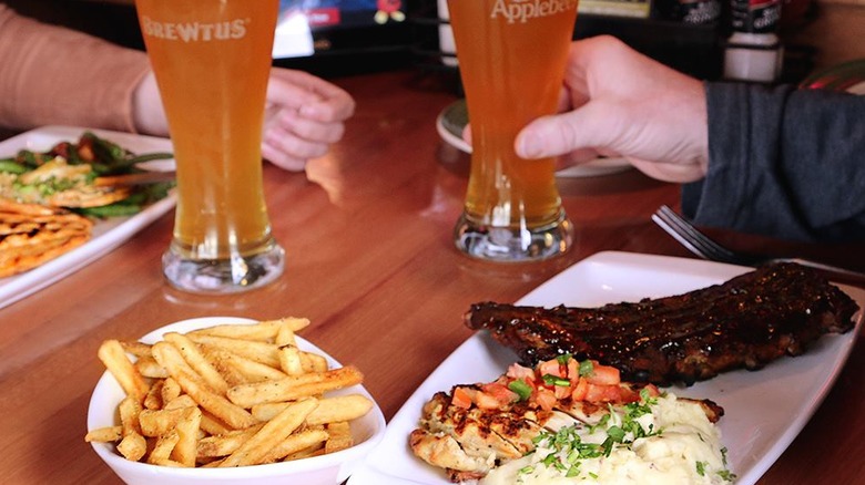 Table at Applebee's with glasses of beer, fries, salmon, chicken, and ribs