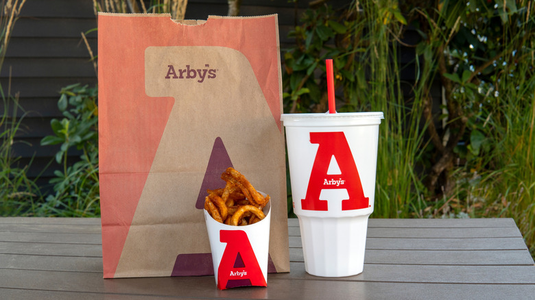 Arby's bag, fries, and drink on a picnic table