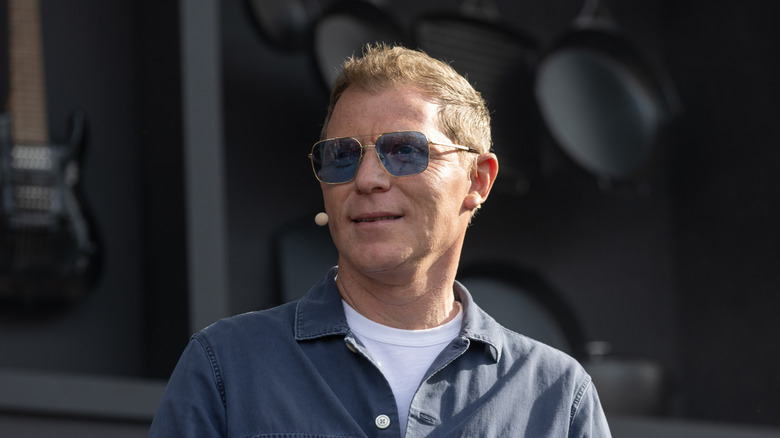 Bobby Flay wearing sunglasses and smiling at a live cooking demonstration