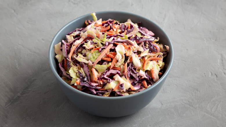 A bowl of lightly dressed coleslaw is bright with orange carrots and purple cabbage.