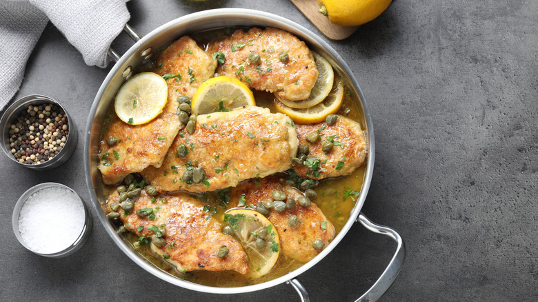 Delicious chicken piccata on grey table, flat lay.