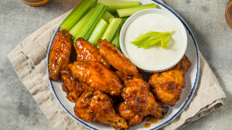 A plate of buffalo wings accompanied by celery and ranch dressing.
