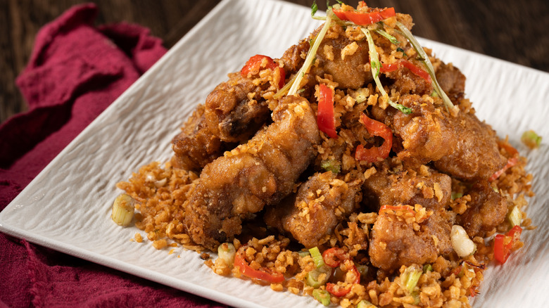 spare ribs on a white plate with fried chilies and garlic