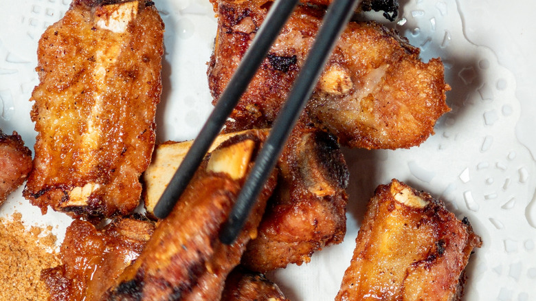 Close up of crispy spare ribs with someone taking a piece using chopsticks