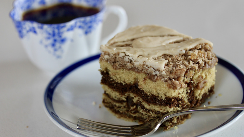 A plate of coffee cake with a cup of coffee in the background