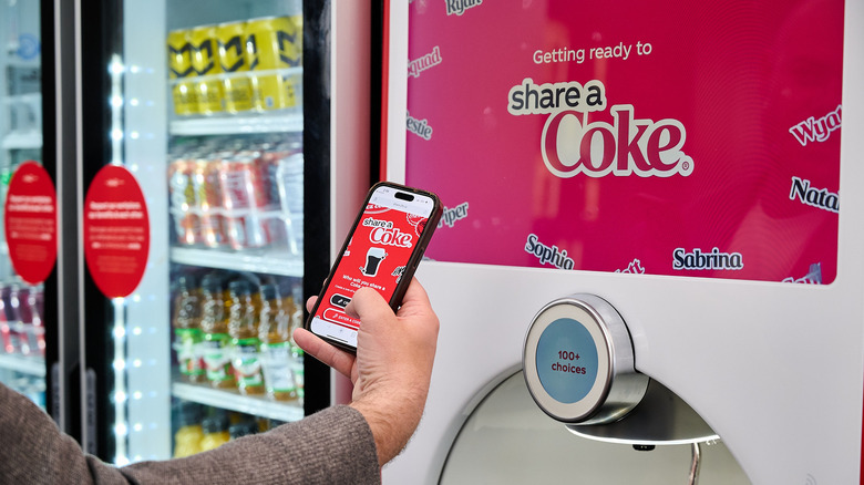 Man's arm holding a phone up to a Freestyle machine