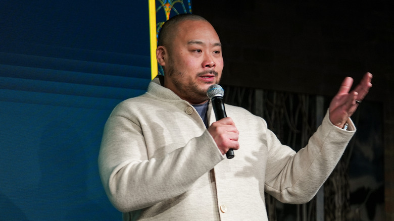 Chef David Chang on stage speaking, holding a microphone.
