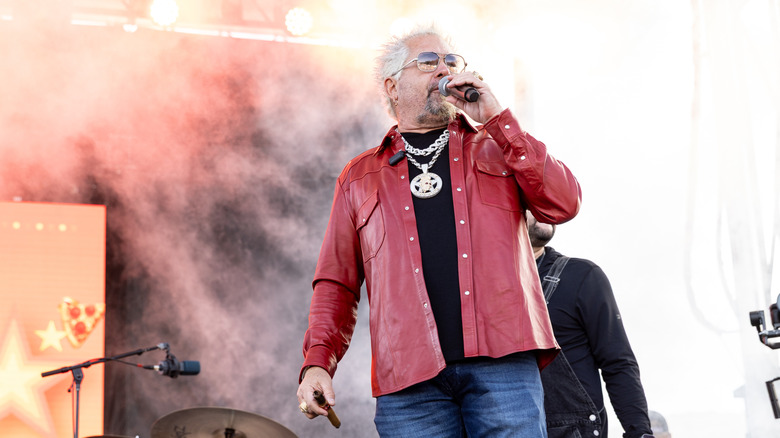 Guy Fieri speaking into a microphone on stage