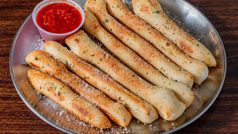 breadsticks displayed in an appetizing way on a silver tray with marinara sauce
