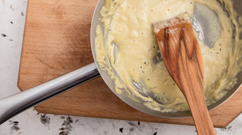 Wood spatula whisking a roux in stainless steel pan