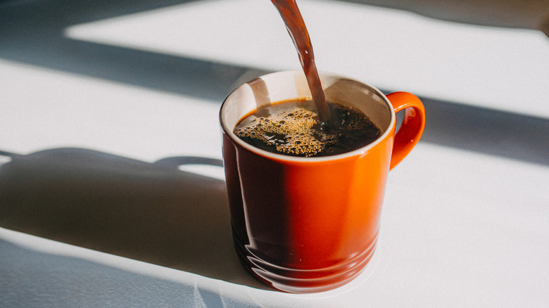 Coffee pouring into orange mug