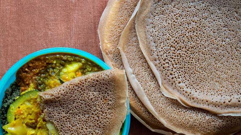 a stack of injera next to a bowl of lentils