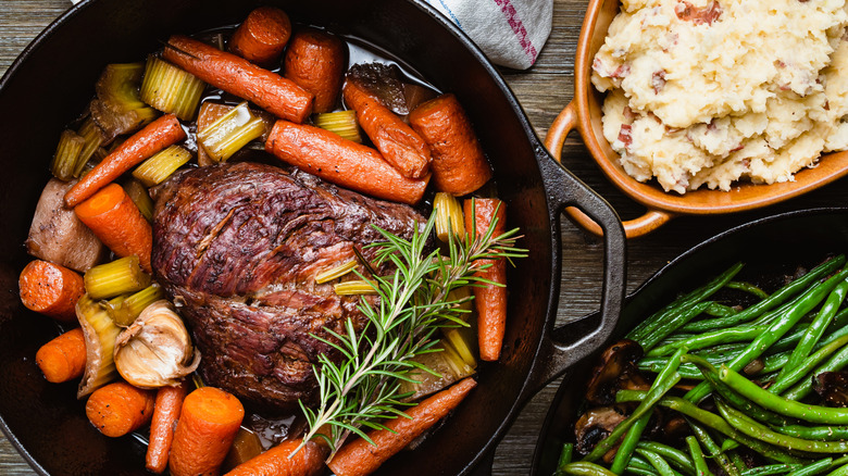 Pot roast has been cooked with carrots and other veggies.