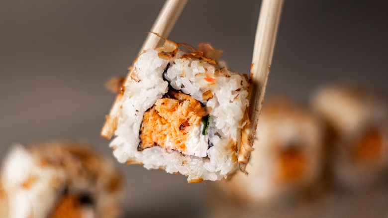 Sushi roll between chopsticks
