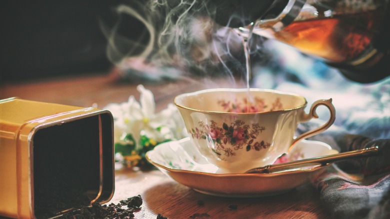 Pouring black tea in a teacup