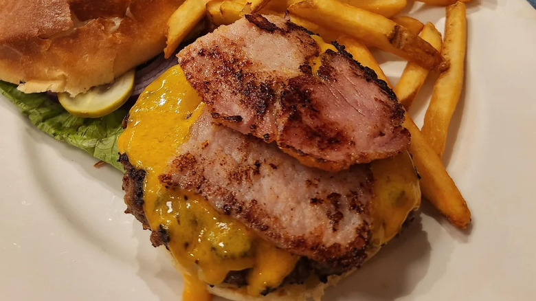 An open-face banquet burger topped with Canadian bacon and cheese, served with fries