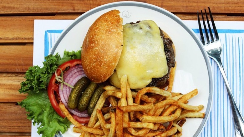 An open-faced french burger made with high quality beef and topped with gruyere cheese, served with frites